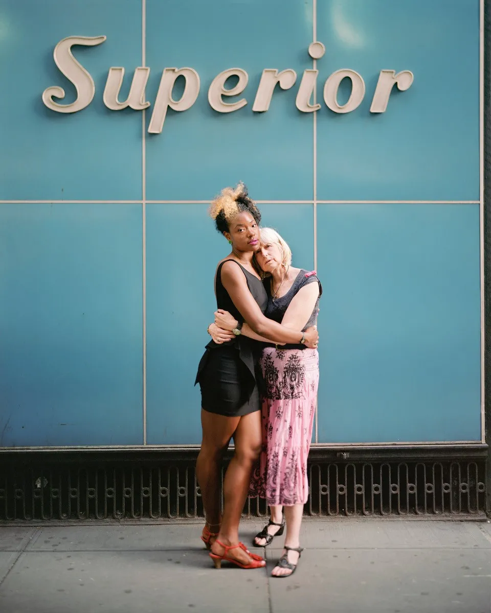 Two people hugging in front a blue wall